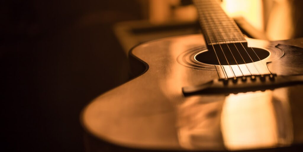 A close up of an acoustic guitar in a dark room.