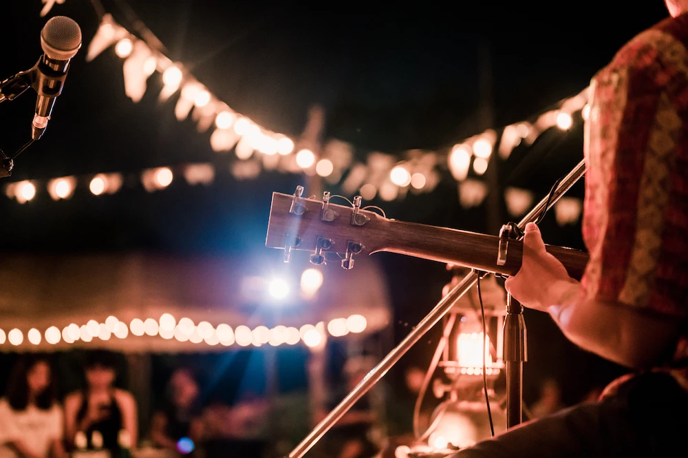 A man playing an acoustic guitar at an outdoor event.